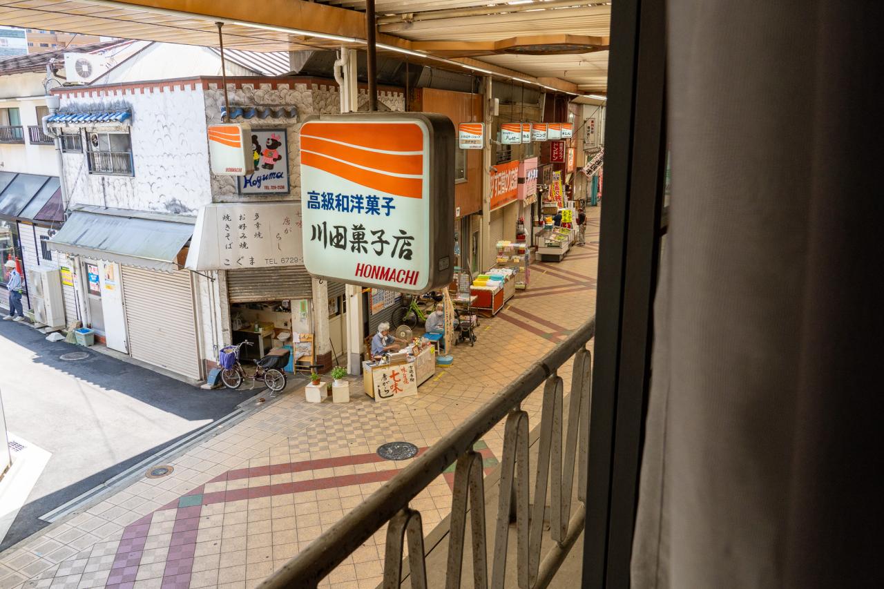 客室の窓をガラガラと開けると、電飾看板越しに望めるのはもちろん商店街。