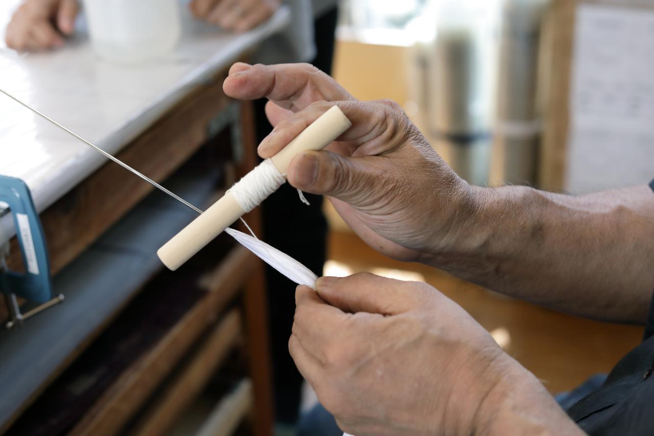 「丸棒の持ち方は鉛筆を持つように」と、村瀬さんが手の使い方を丁寧に教えてくれる。